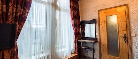 A room with a wooden door, a bench, and a TV mounted on the wall.