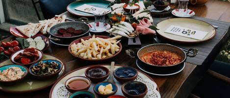 A table set with various dishes and drinks, including cheese, meats, and fruits, suggesting a meal setup.