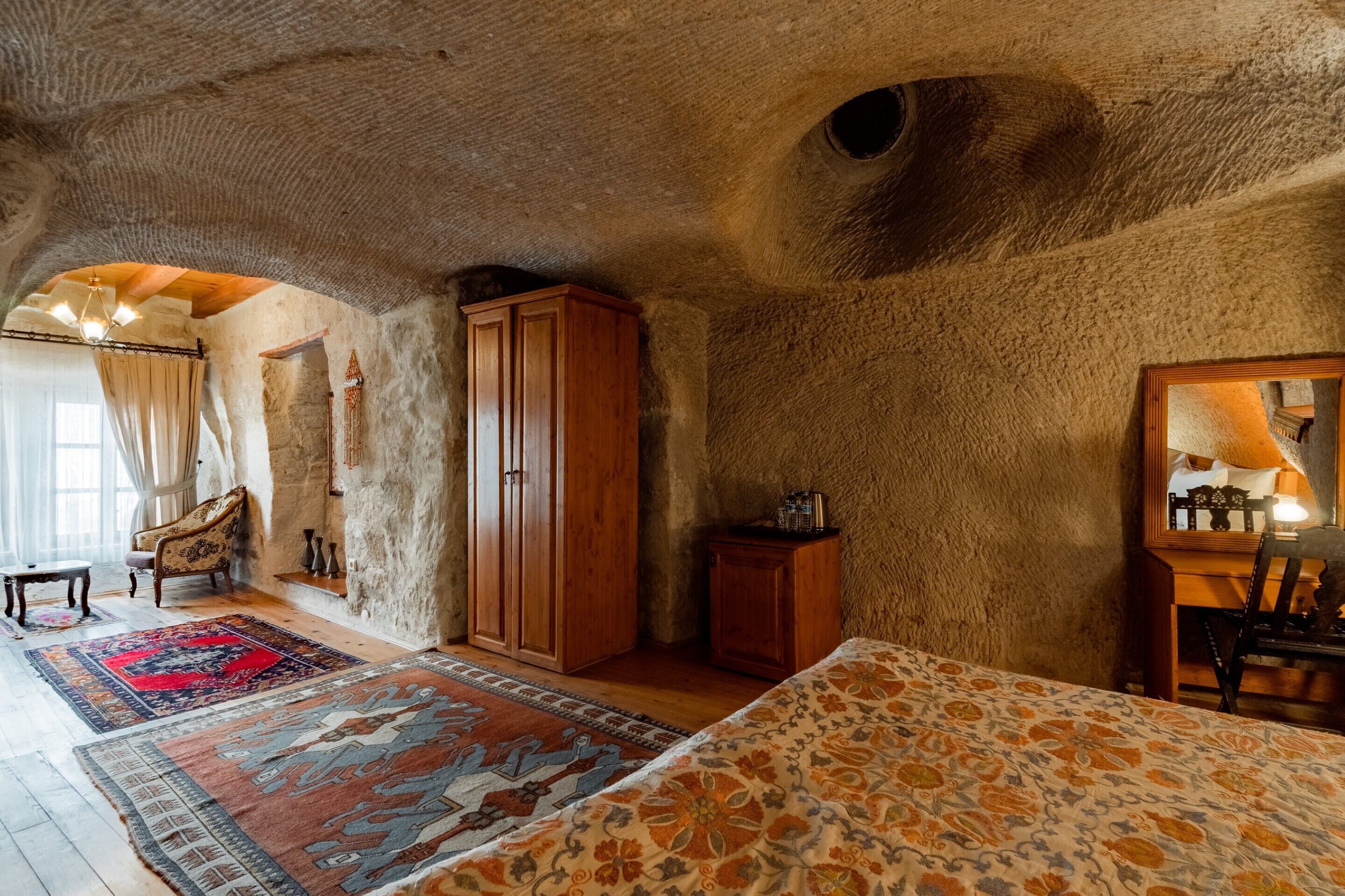 A room with a stone ceiling, wooden furniture, and a large bed.