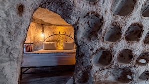 Een gezellige kamer met een bed, een wandlamp en een rustieke stenen muur.