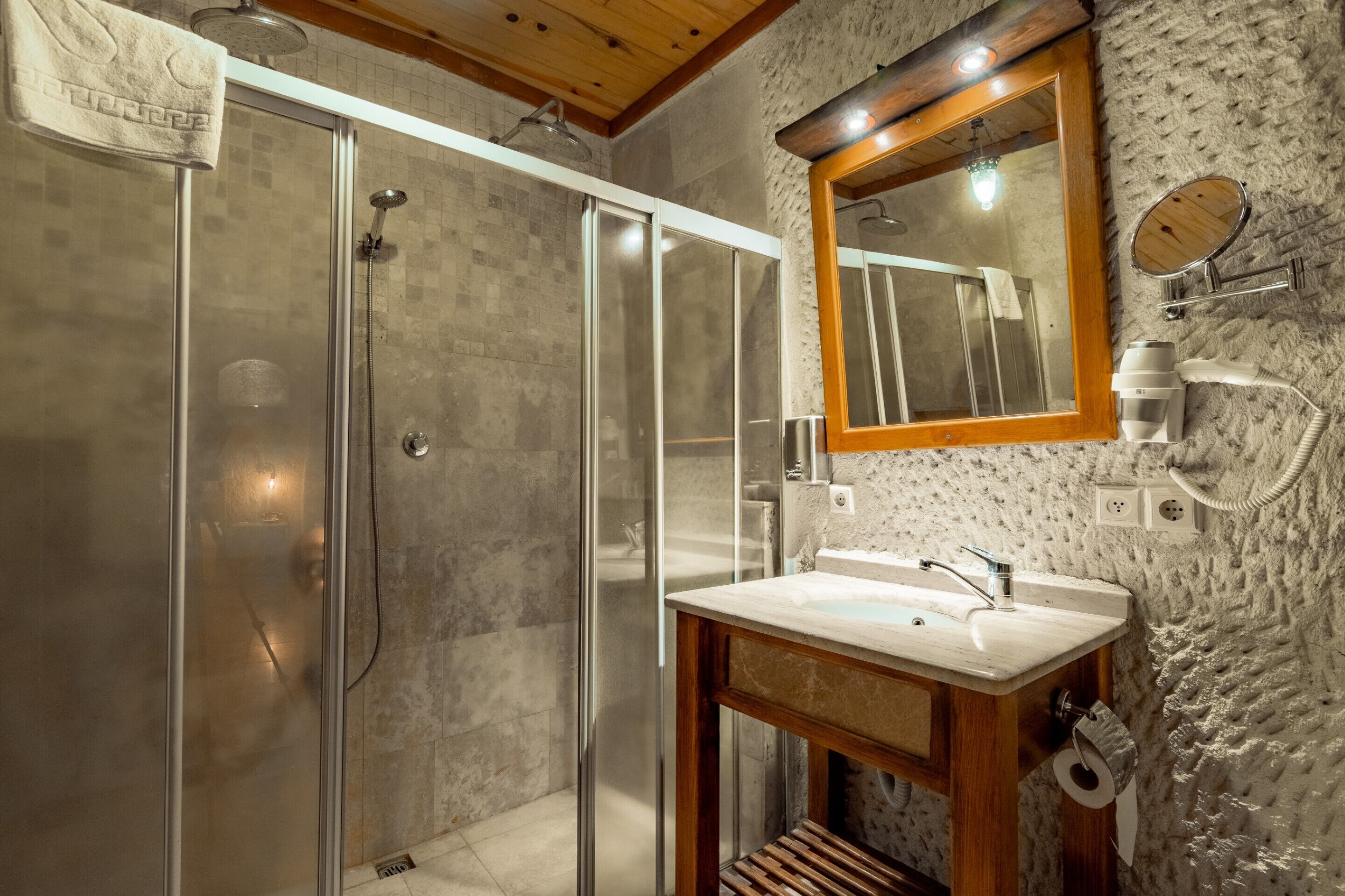 A modern bathroom with a glass-enclosed shower, a wooden vanity, and a large mirror.