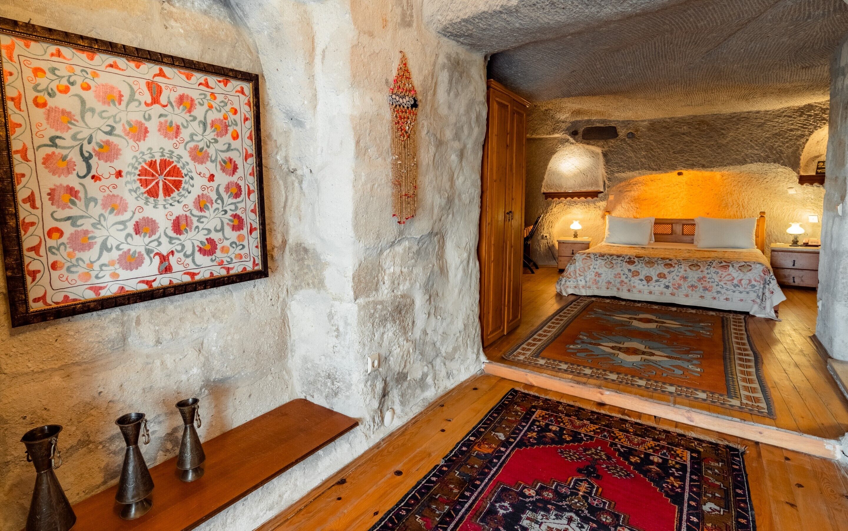 Un dormitorio rústico con una cama de madera, un tapete estampado y un colgador tradicional en la pared.