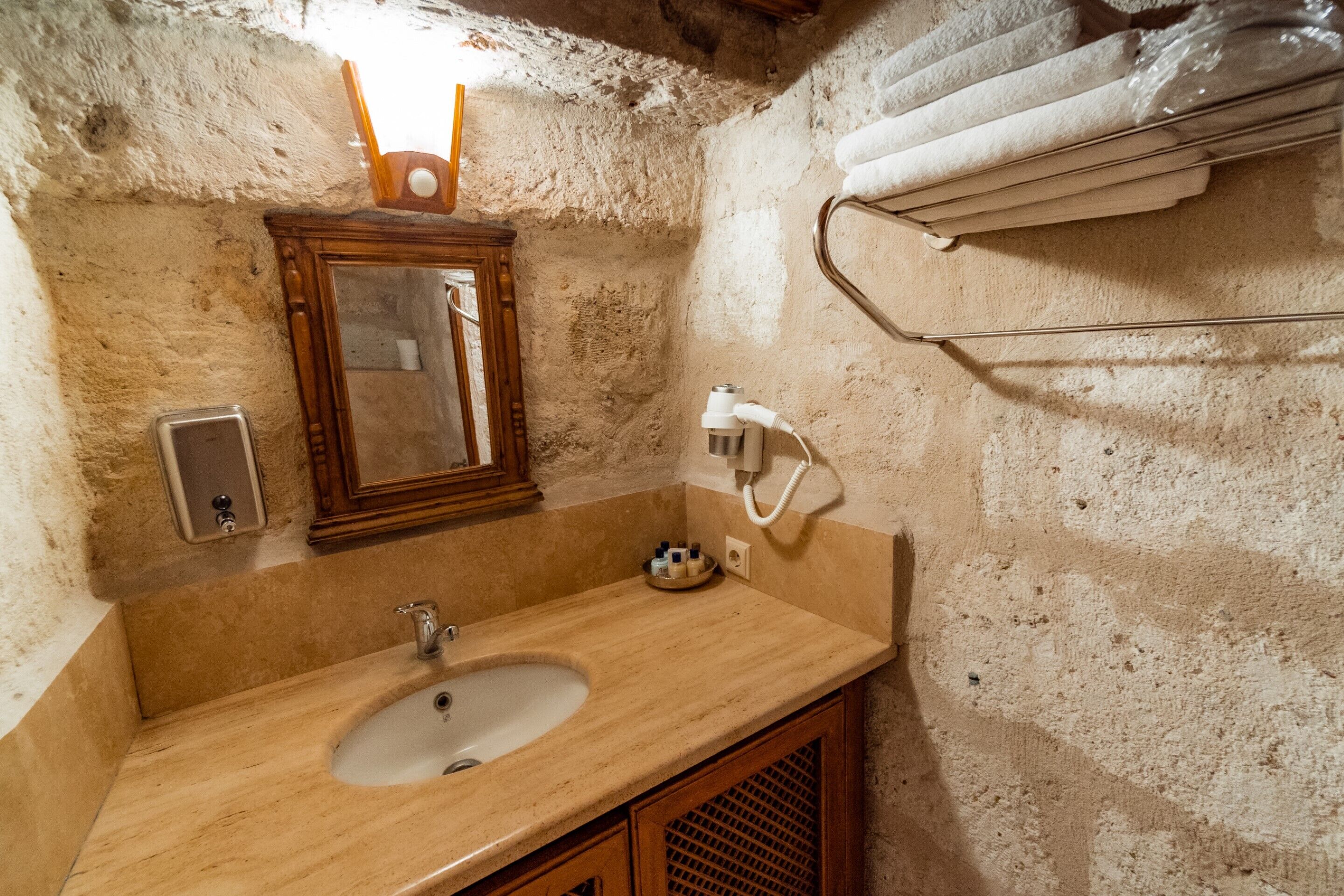 A bathroom with a sink, mirror, towel rack, and a hand dryer.