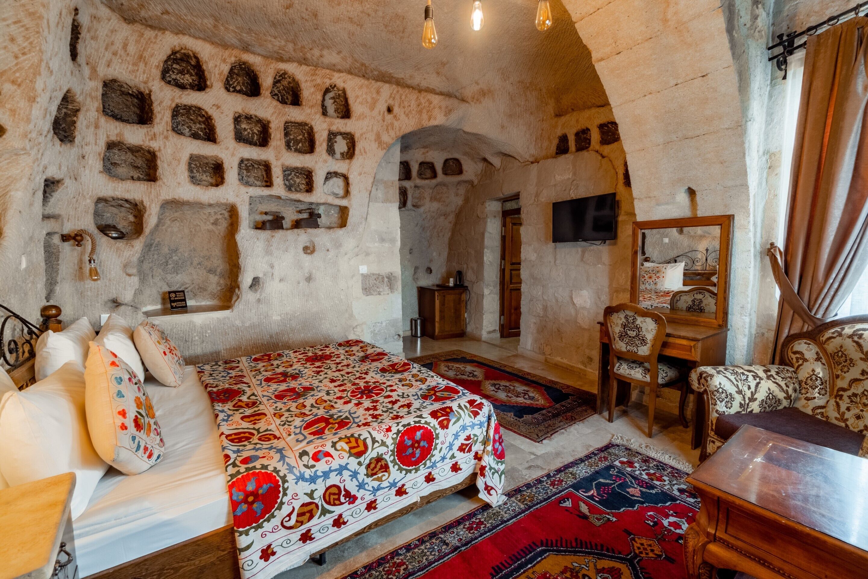 A traditional room with a bed, a wooden chair, a small table, and a television.