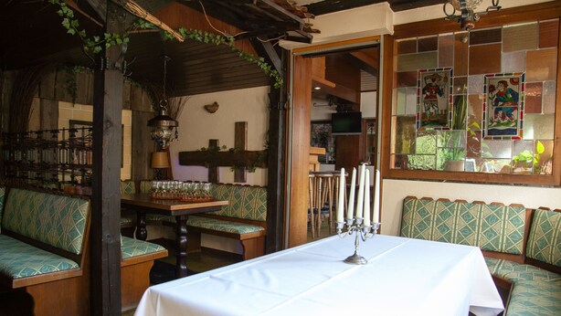 Un rincón comedor acogedor con una mesa preparada para dos, bancos de madera y una ventana de vitral.