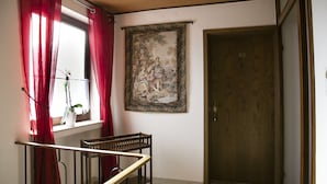 Una escalera con barandilla de madera, una ventana con cortinas rojas y una puerta con el símbolo del número.