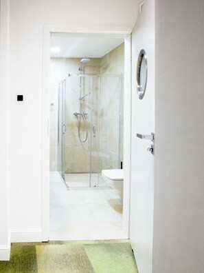 A modern bathroom with a glass-enclosed shower, a toilet, and a sink. - Gold Apartments (Wroclaw)