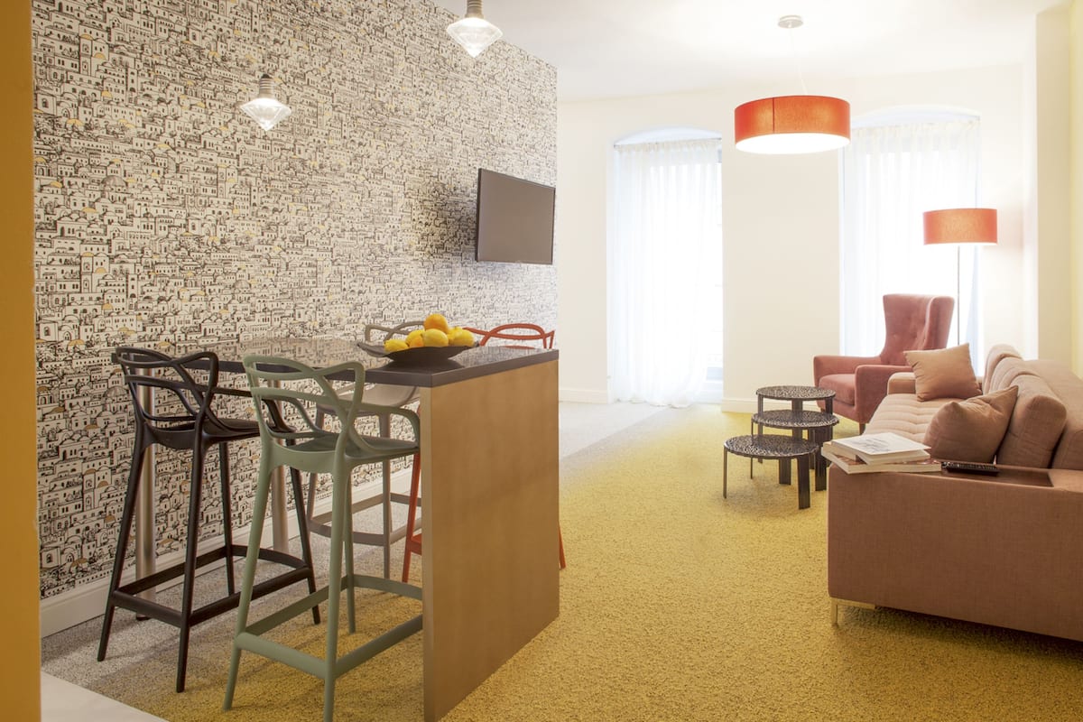 Ein modernes Wohnzimmer mit einer Couch, Sesseln, einem Couchtisch und einem Fernseher.