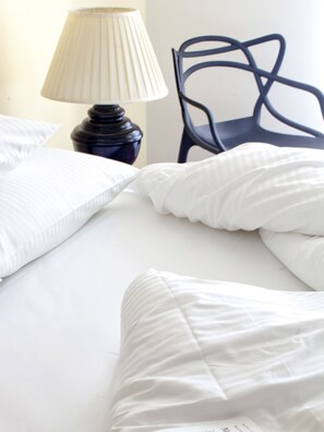 A neatly made bed with white linens and a dark blue chair in the background. - Gold Apartments (Wroclaw)
