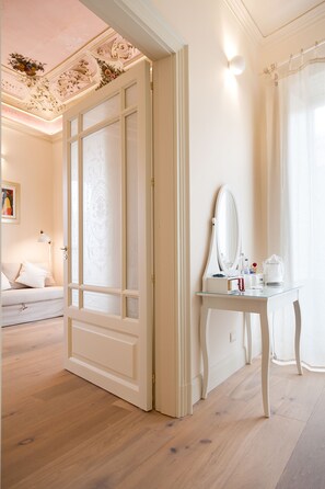 Une pièce avec un grand miroir, une petite table avec des articles de toilette et une porte blanche.