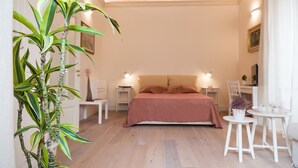 A bedroom with a bed, bedside tables, a potted plant, and a small table with a chair.