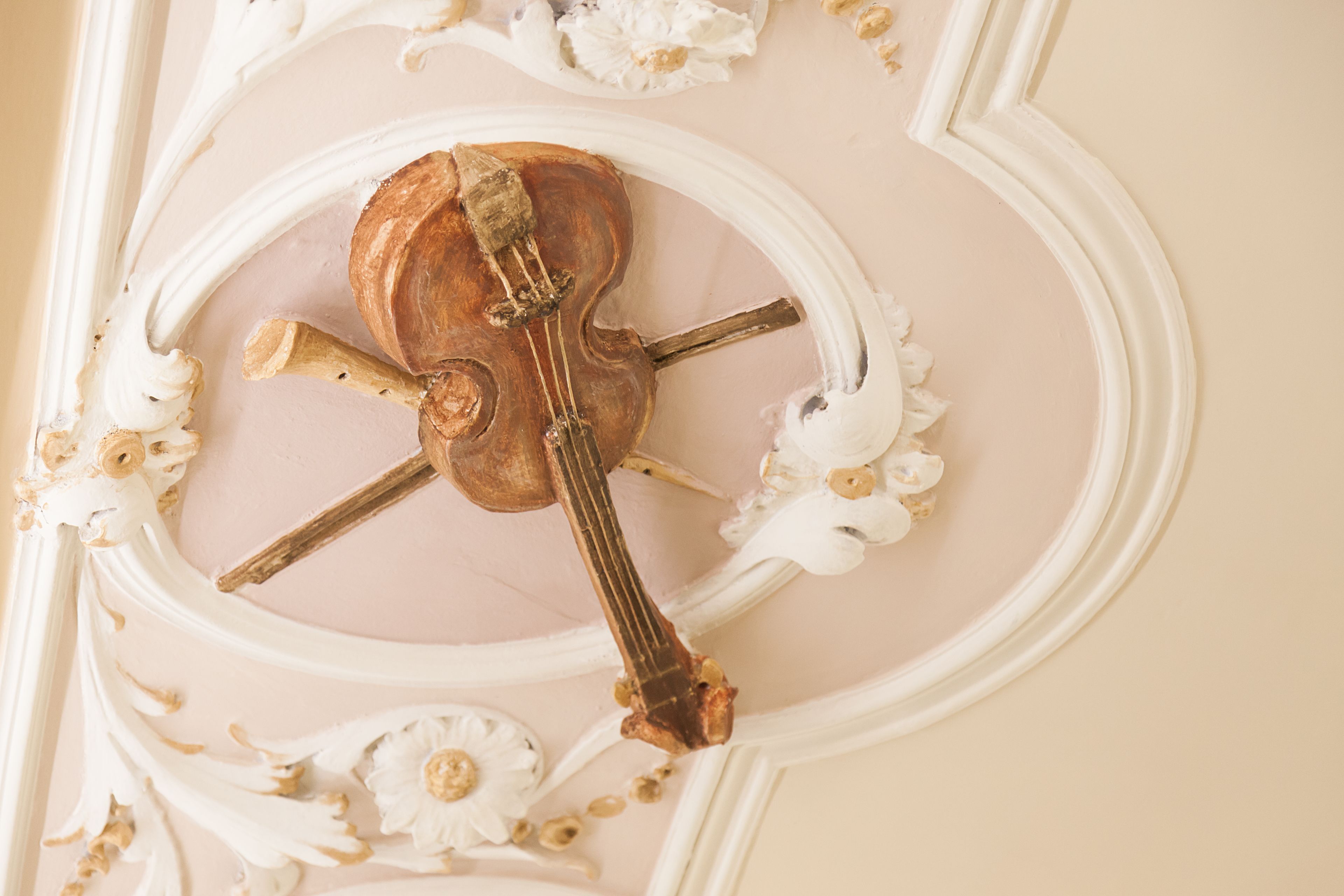 A ceiling with a decorative clock featuring a violin and bow.