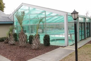A conservatory with a glass structure, surrounded by landscaped shrubs and a street lamp. - Maison Layaway (Myrtle Beach)