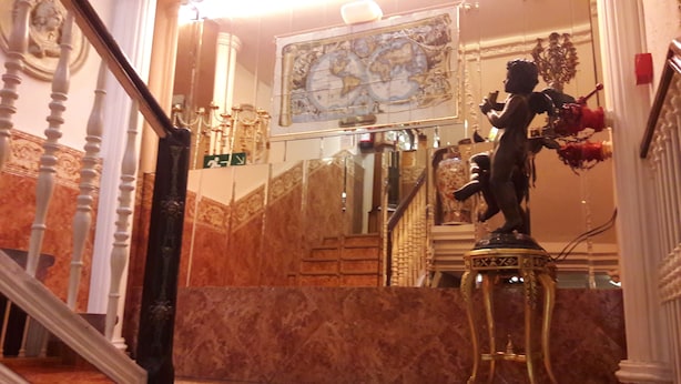A grand staircase with ornate railings, a marble floor, and a statue of a cherub. - Dato 2 (Vitoria-Gasteiz)
