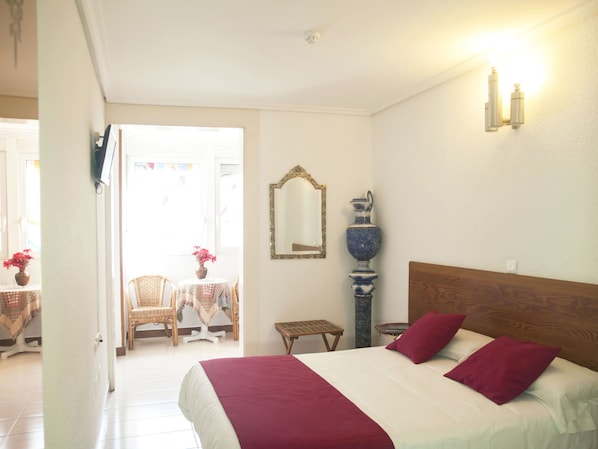 A hotel room with a bed, a mirror, a vase, and a small table. - Dato 2 (Vitoria-Gasteiz)