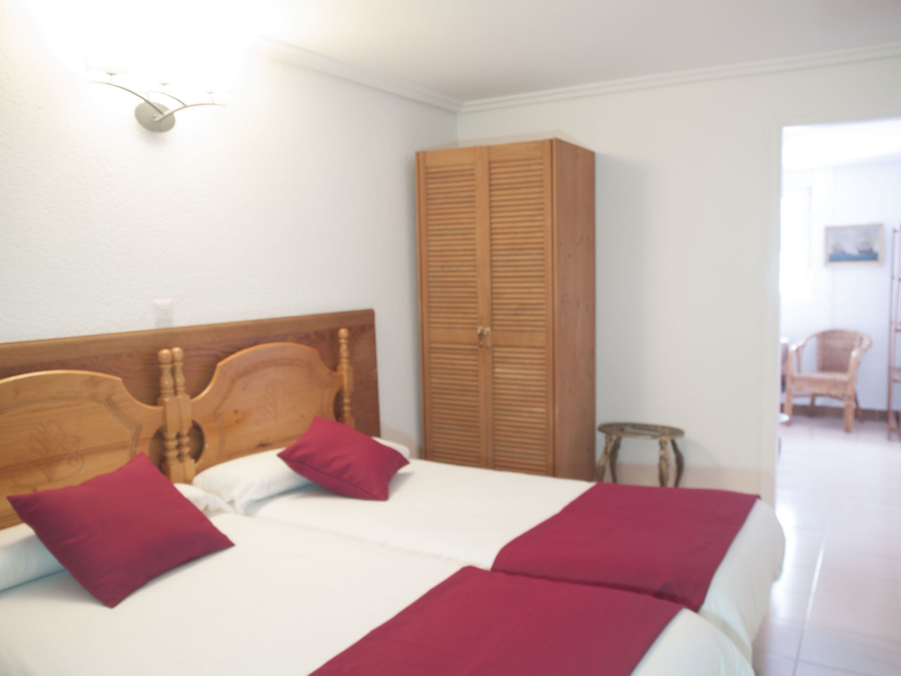 Een slaapkamer met twee bedden, houten hoofdborden en een kledingkast.