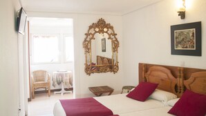 A hotel room with two beds, a wooden headboard, a large ornate mirror, a small table with a chair, and a picture on the wall. - Dato 2 (Vitoria-Gasteiz)