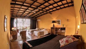 A cozy room with a bed, two chairs, a desk, and a window overlooking a deck. - El Soberbio Lodge (El Soberbio)