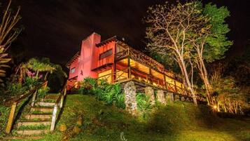A two-story building with a red facade, a wooden deck, and a stone staircase leading up to the entrance.