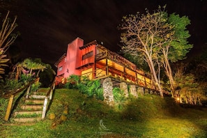 A two-story building with a red facade, a wooden deck, and a stone staircase leading up to the entrance. - El Soberbio Lodge (El Soberbio)