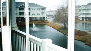 En utsikt från ett fönster med utsikt över ett bostadsområde, där en byggnad med ett platt tak och flera fönster syns.
