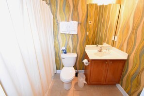 A bathroom with a toilet, sink, and wooden cabinets. - 911 Willow Bend (North Myrtle Beach)