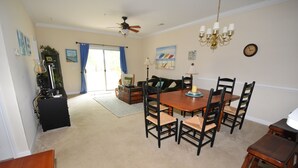 A dining area with a wooden table and chairs, a ceiling fan, and a chandelier. - 612 Willow Bend (North Myrtle Beach)