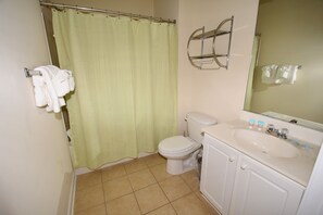 A bathroom with a toilet, sink, and shower curtain.