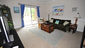 A living room with a sofa, a wooden chest, a desk with a computer, and a lamp. - 612 Willow Bend (North Myrtle Beach)