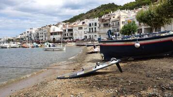 Enjoy a leisurely stroll along the rocky coastline, where boats bob gently in the water and a surfboard lies on the beach, inviting you to explore the area's boating and recreational activities.