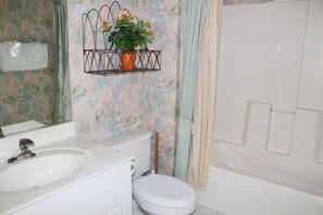 A bathroom with a white sink, toilet, and bathtub. There is a hanging plant above the sink. - 223 Wedgewood (North Myrtle Beach)