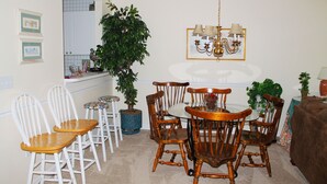 A dining area with a round table and chairs, a potted plant, and a chandelier. - 223 Wedgewood (North Myrtle Beach)
