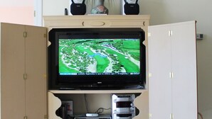 A television mounted on a cabinet with a golf course displayed on the screen. - 223 Wedgewood (North Myrtle Beach)