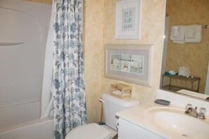 A bathroom with a bathtub, toilet, sink, and a shower curtain.