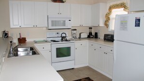 A kitchen with white cabinets, a microwave, stove, sink, toaster, blender, and refrigerator. - 432 Willow Bend (North Myrtle Beach)