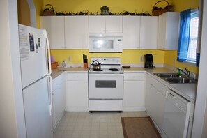 Kitchen equipped with a refrigerator, microwave, oven, and dishwasher, along with a kettle and coffee maker.