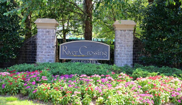 River Crossing entrance features a beautifully maintained garden with a variety of flowering plants.