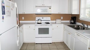 A kitchen with white cabinets, a built-in microwave, a stove, a dishwasher, and a sink. - 522 Ironwood (North Myrtle Beach)