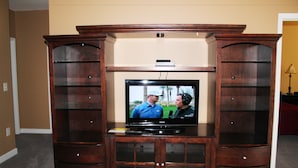 A television set on a wooden entertainment center with glass shelves. - 522 Ironwood (North Myrtle Beach)