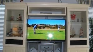 A flat-screen TV mounted on a cabinet with shelves on either side. - 332 Edgewater (North Myrtle Beach)