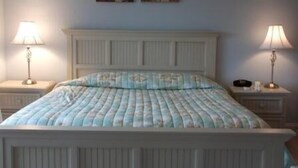 A bedroom with a bed, two bedside lamps, and two wall-mounted paintings. - 332 Edgewater (North Myrtle Beach)