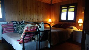 A wooden cabin room with a bed, two bedside tables with lamps, and a window.