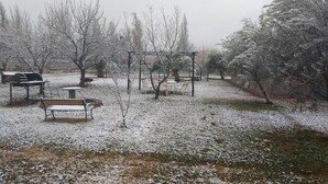 A park with benches and a barbecue grill covered in snow. - Finca Fisterra (Fray Luis Beltrán)