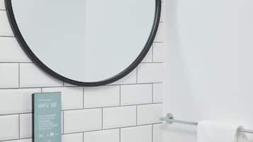 Un baño con un lavabo blanco, un espejo redondo con marco negro y un letrero sobre jabón ecológico.