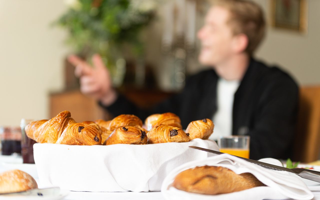 Een ontbijttafel met croissants en een glas sinaasappelsap.