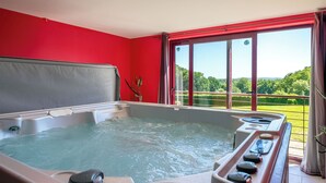 Un jacuzzi con vistas a un paisaje verde a través de amplios ventanales.