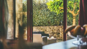 Vista desde el interior de una habitación con muebles de mimbre y una pared de piedra.