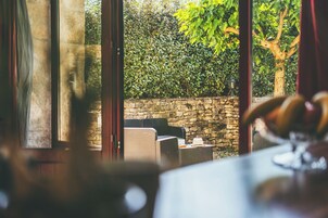 A view from inside a room with wicker furniture and a stone wall outside.