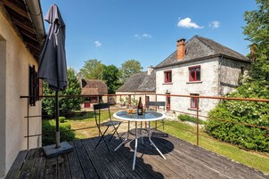 A wooden deck with a round table and chairs, a bottle, and a plate of food.