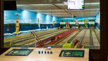 Een bowlingbaan met een muurschildering van een strand en een scorebord.